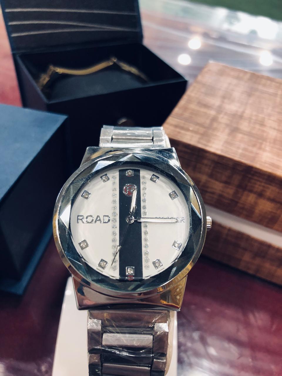 Silver wristwatch with a white face on a wooden surface