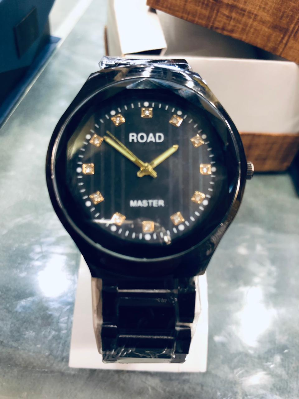 Black wristwatch with 'ROAD' branding on a reflective surface