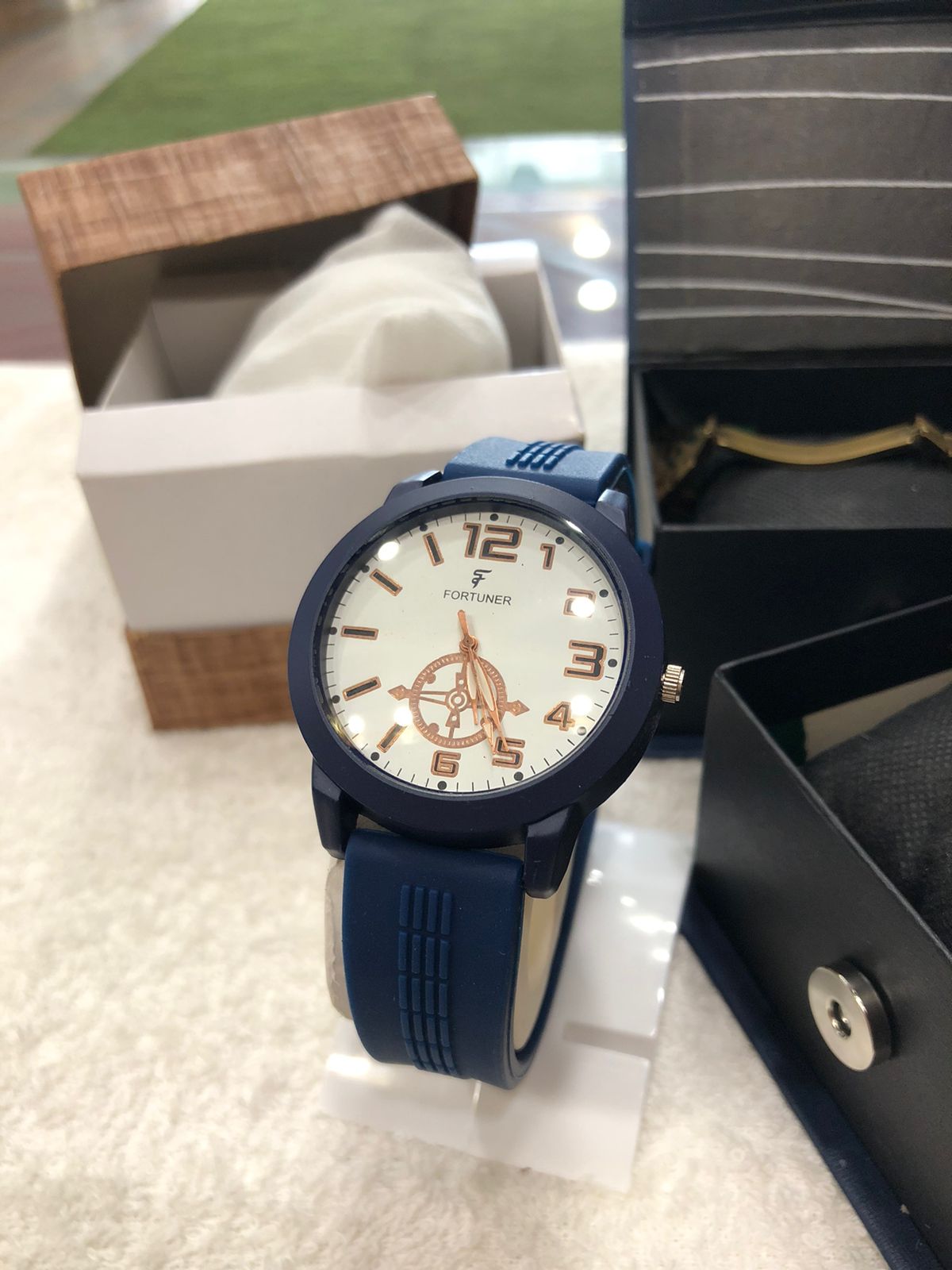Blue wristwatch with white face and brown accents on a light surface