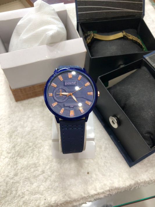 Blue watch with orange accents on a white surface, surrounded by packaging