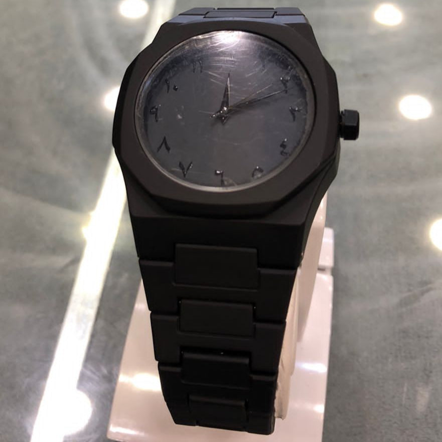 Black watch on a glass surface with a blurred background