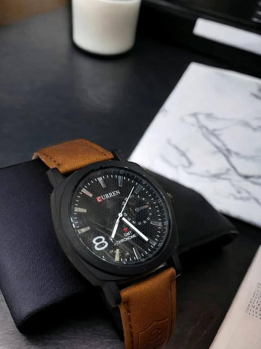 Black watch with brown leather strap on a dark surface