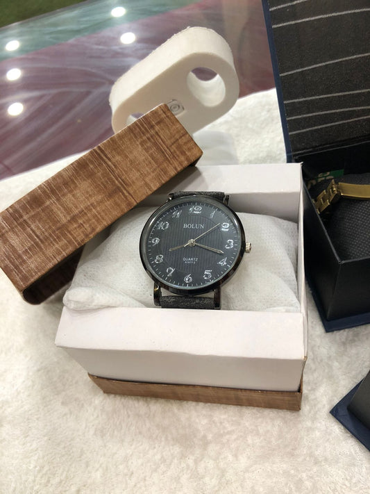 Black watch in a white box with a wooden box and black case in the background.