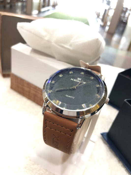 Watch with brown leather strap on a blurred indoor background
