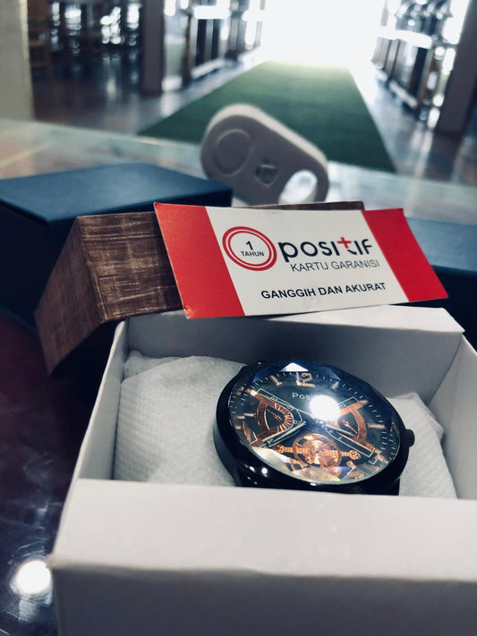Watch in a box with a 'Opositif' card on a blurred background
