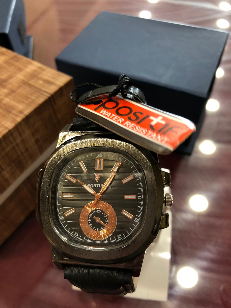 Vintage watch with black strap and detailed face on a reflective surface