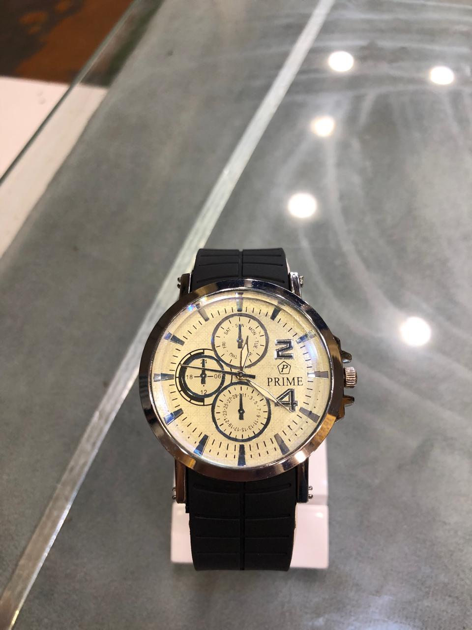 Black wristwatch with a gold face on a reflective surface