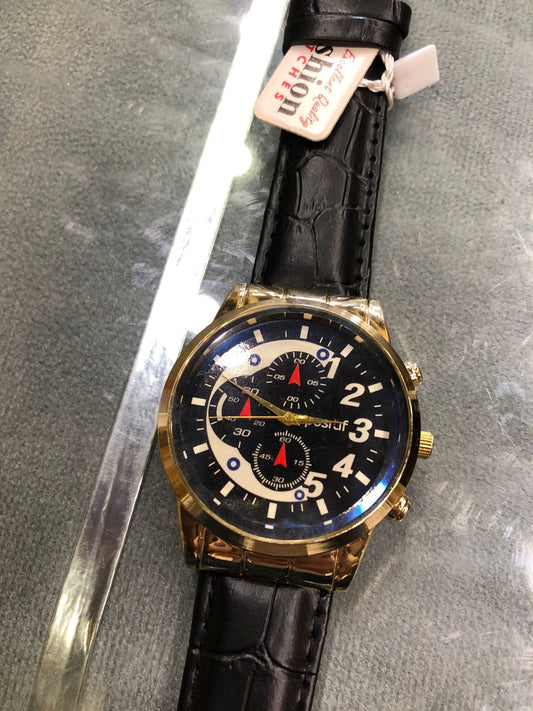 Wristwatch with black leather strap and gold case on a gray surface