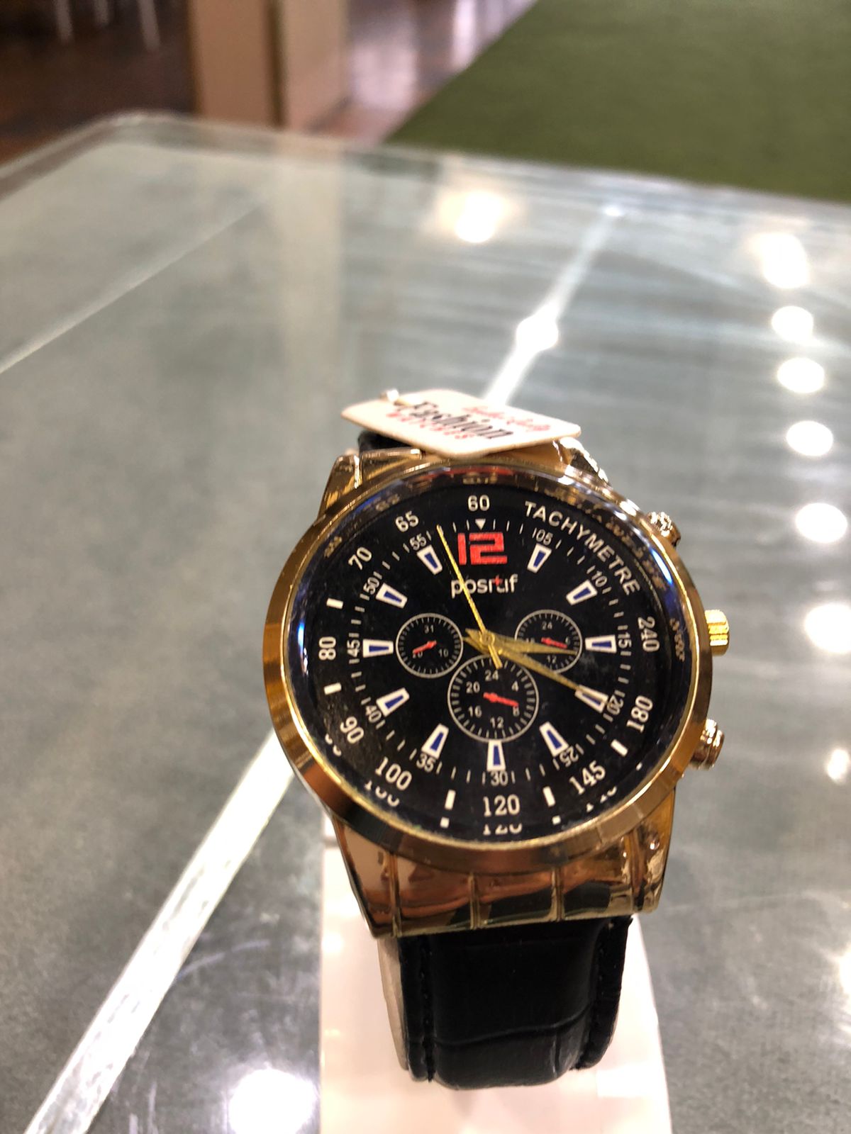 Gold and black watch on a reflective surface